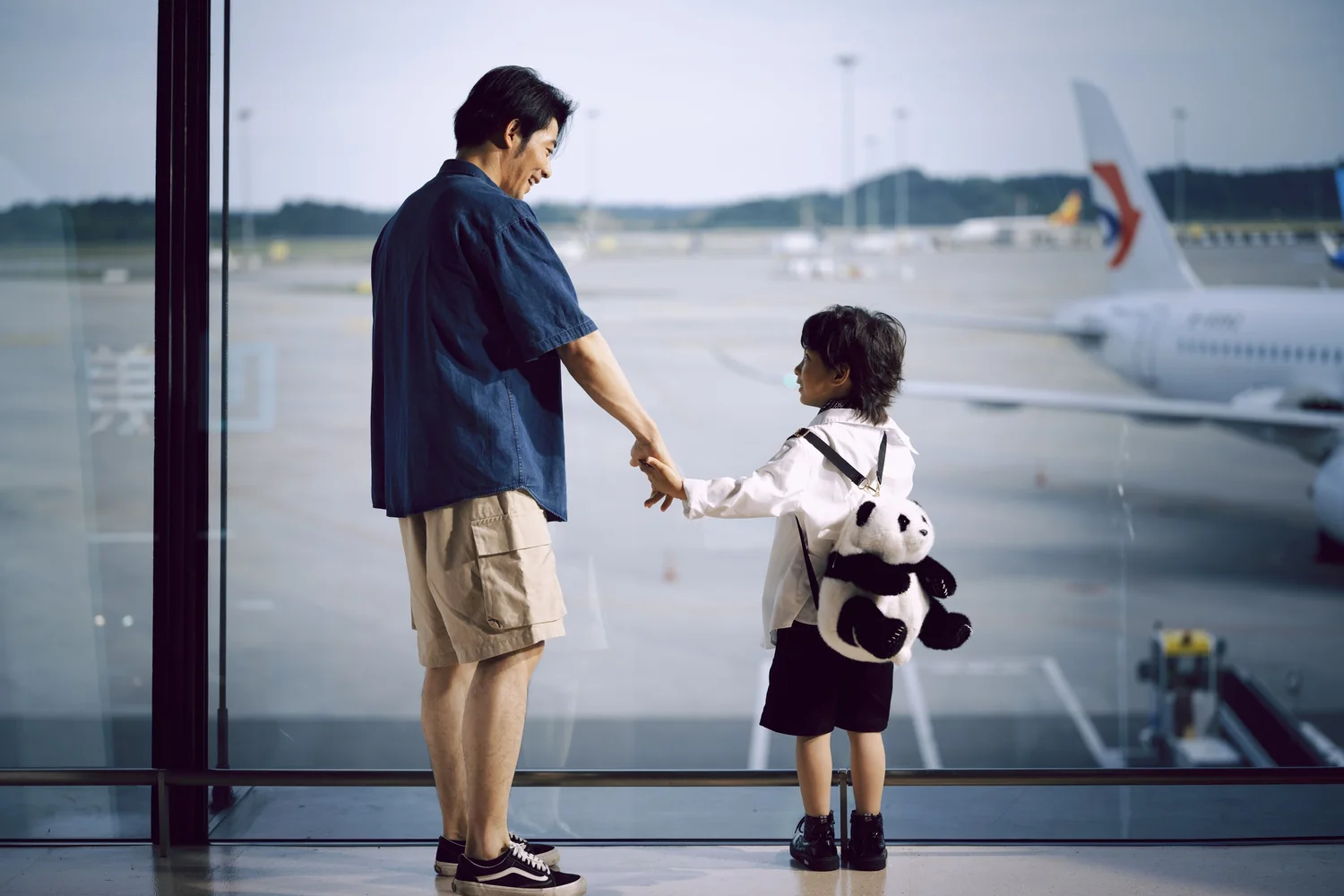 Parent and child watching aircraft before a trip that needs a travel consent document