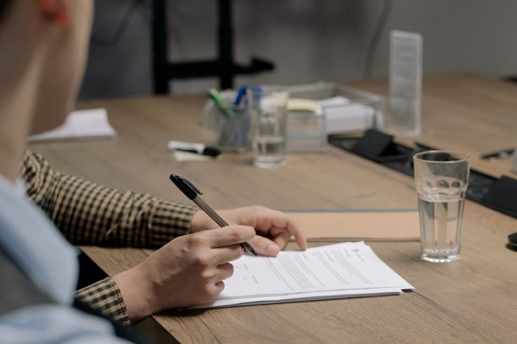 Person signing papers at a wooden table during POA typing services in Dubai